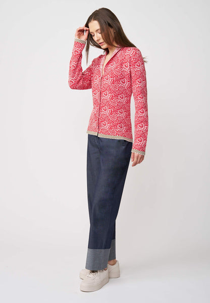 Strickjacke, Modell Jolie in tomatenrot mit weißem floralem Muster und kontrastierendem Saum, seitliche Ansicht getragen