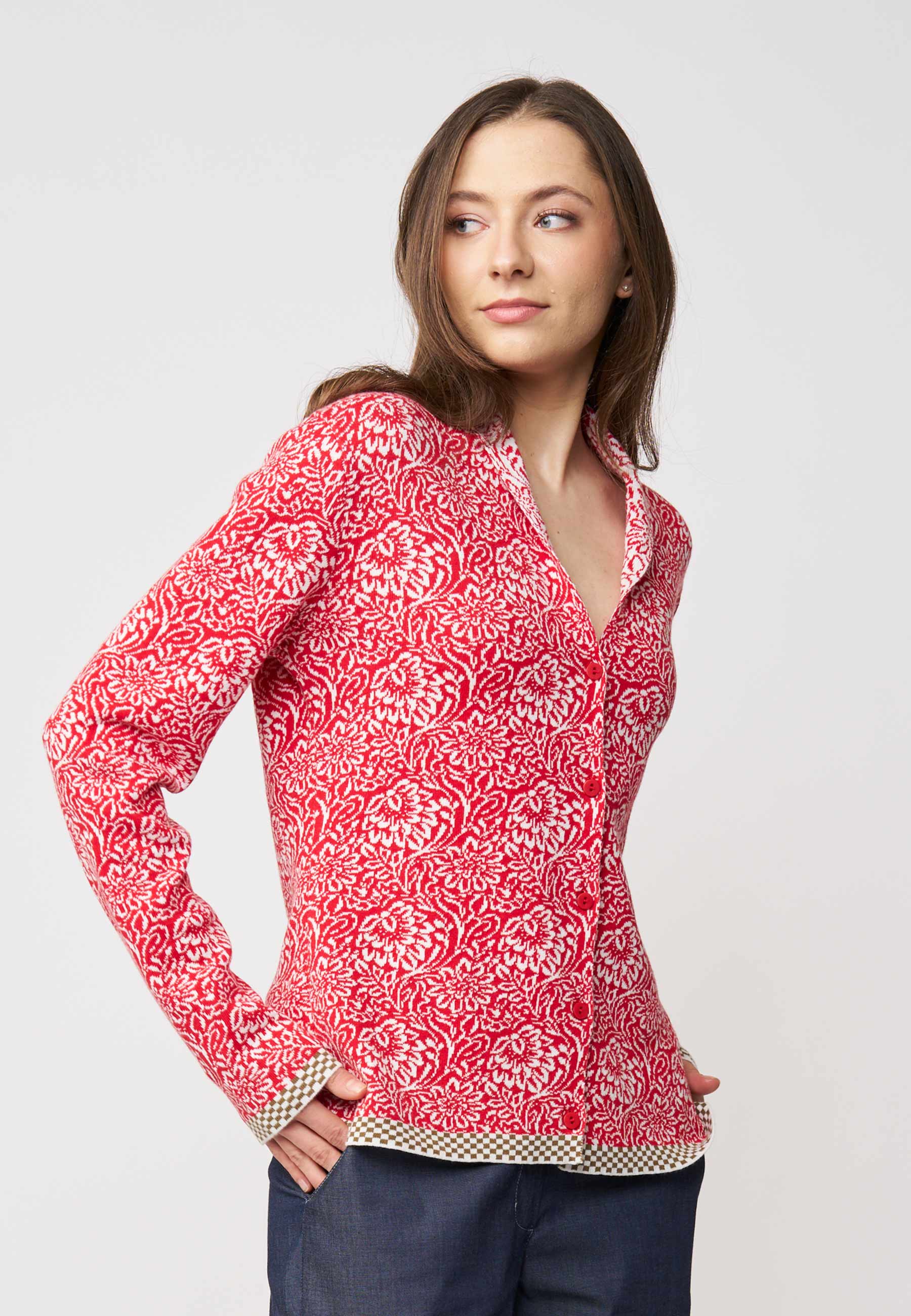 Strickjacke, Modell Jolie in Tomatenrot mit cremefarbenem floralen Muster und kontrastierendem Saum, seitliche Ansicht getragen
