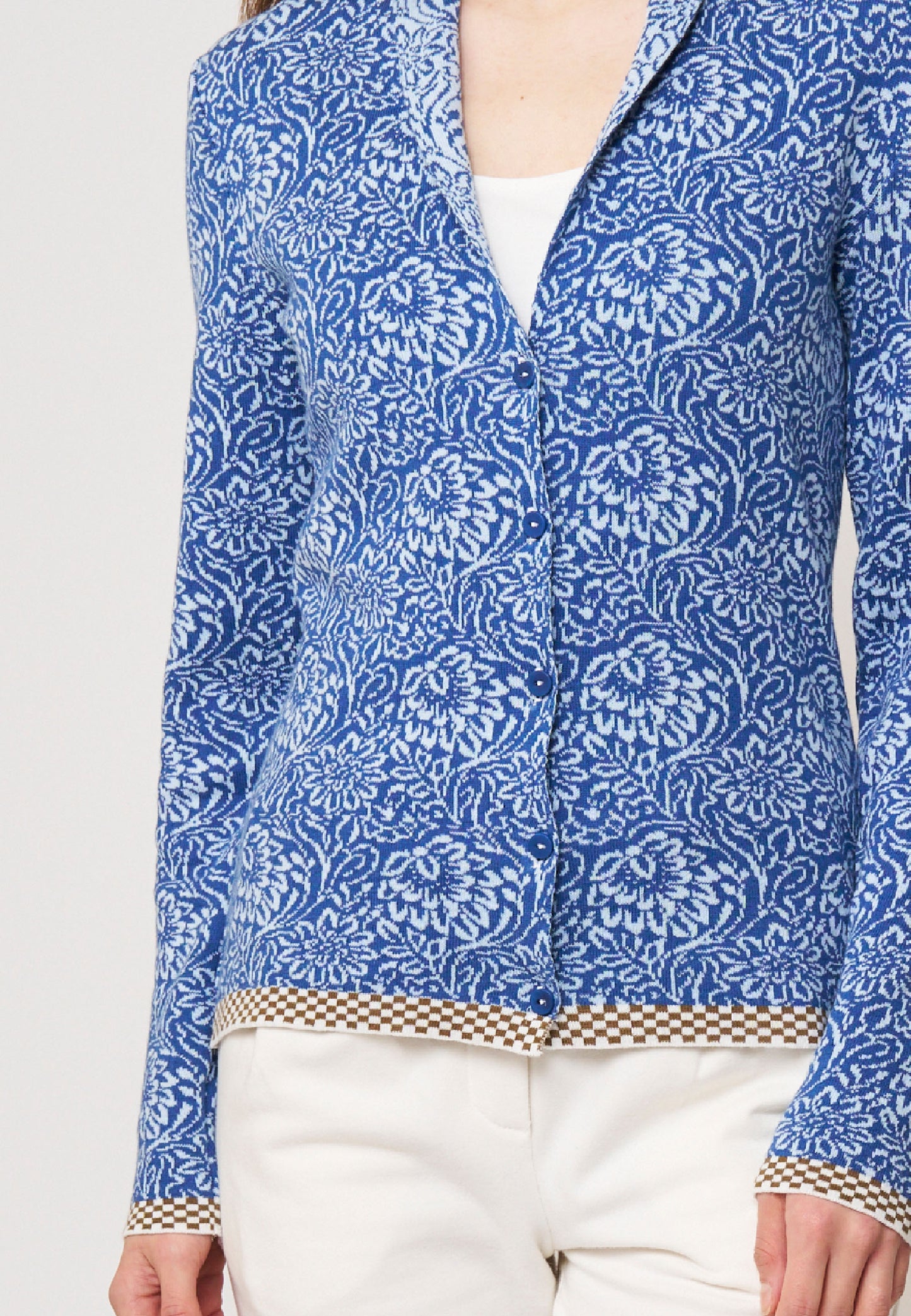 Strickjacke, Modell Jolie in Blau mit weißem floralen Muster und braunem Karomuster am Saum, frontale Ansicht getragen