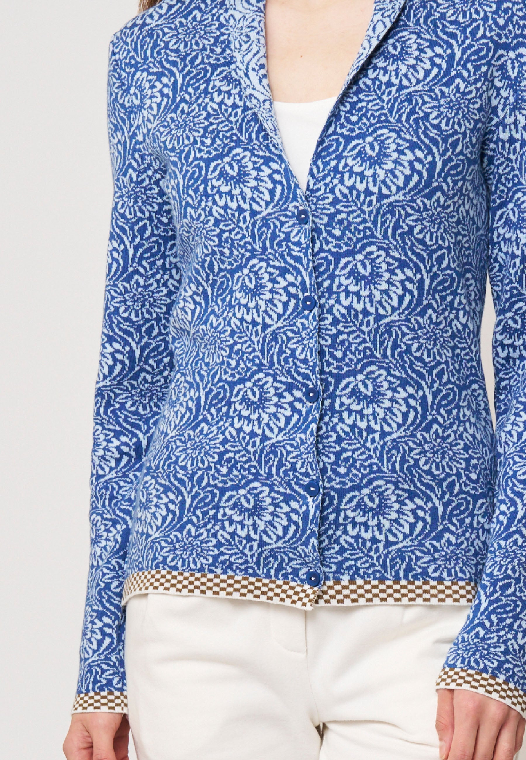 Strickjacke, Modell Jolie in Blau mit weißem floralen Muster und braunem Karomuster am Saum, frontale Ansicht getragen