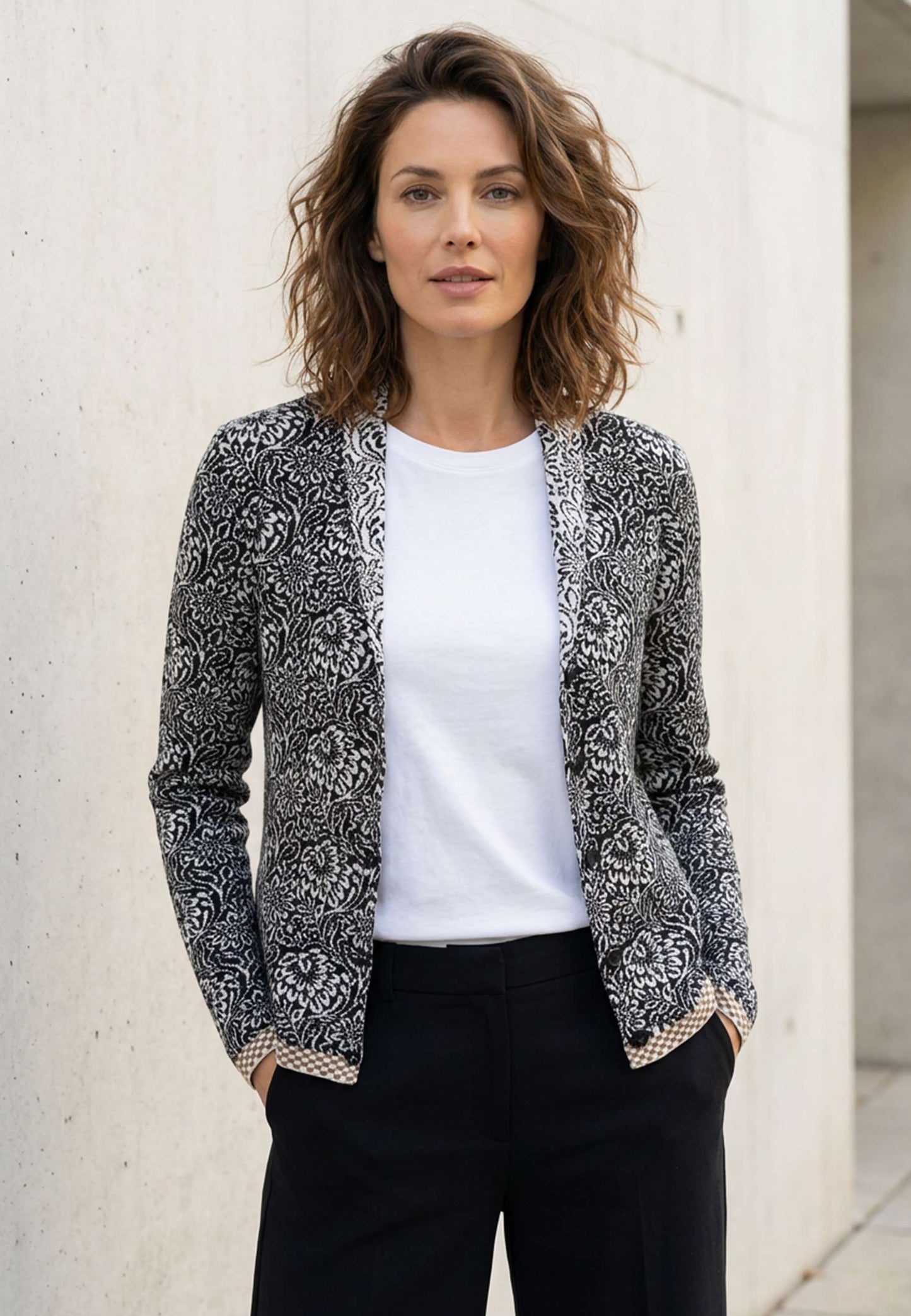 Strickjacke, Modell Jolie in schwarz-ecru mit floralem Muster und kontrastierendem Saum, frontal getragen
