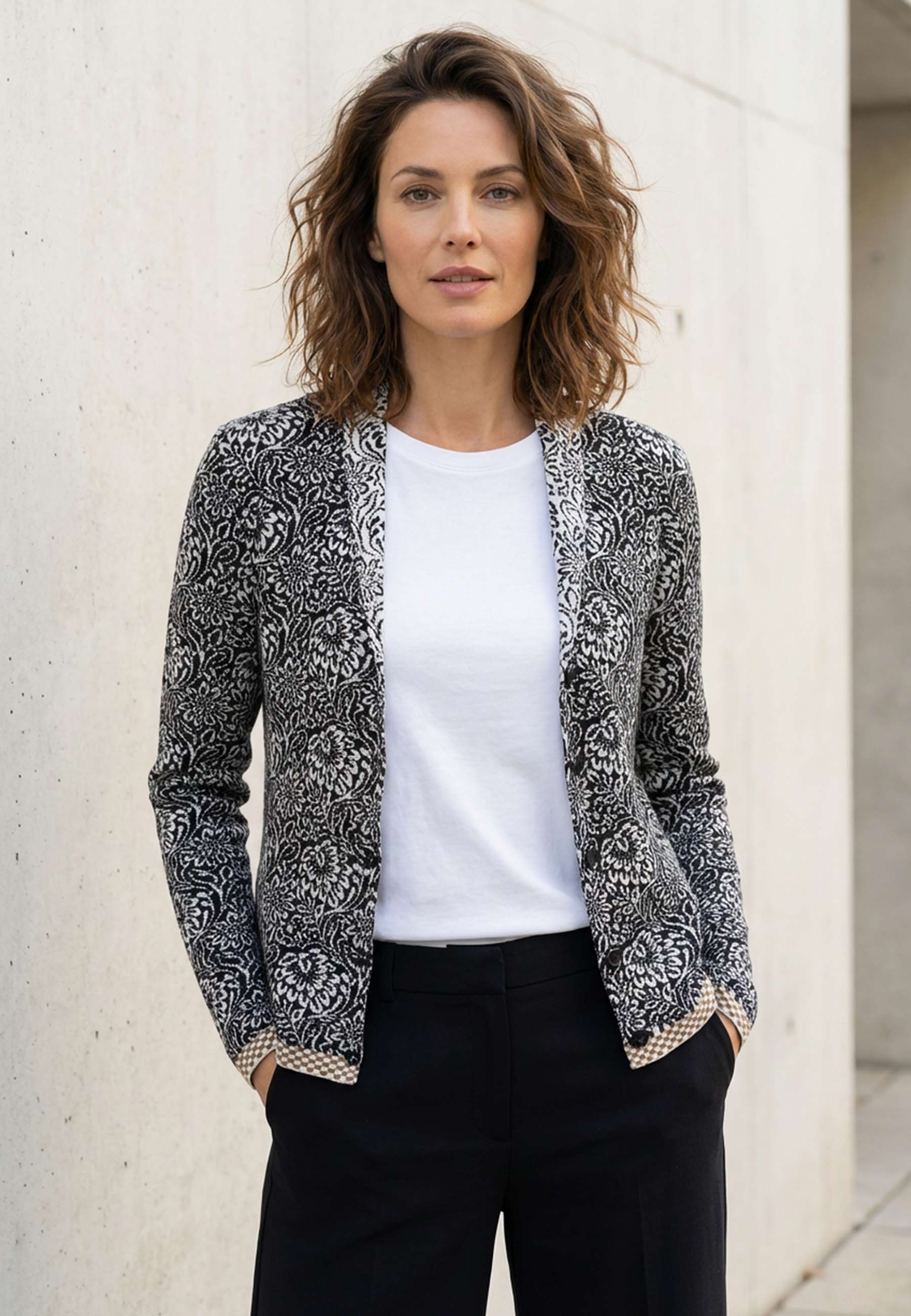 Strickjacke, Modell Jolie in schwarz-ecru mit floralem Muster und kontrastierendem Saum, frontal getragen