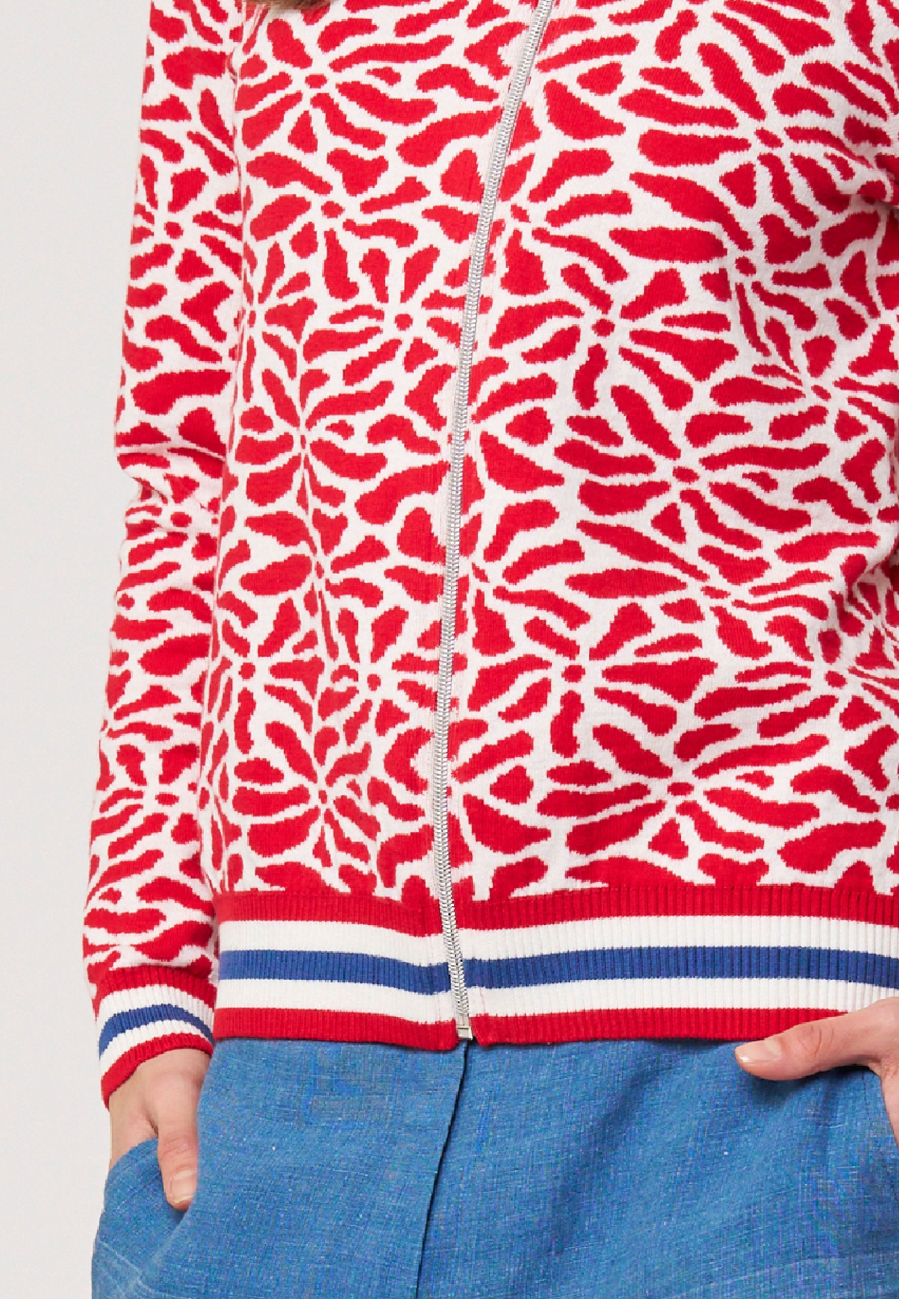 Strickjacke, Modell Alsora in Weiß-Rot mit grafischem Muster und sportlichem Bündchen am Saum, halbseitlich getragen
