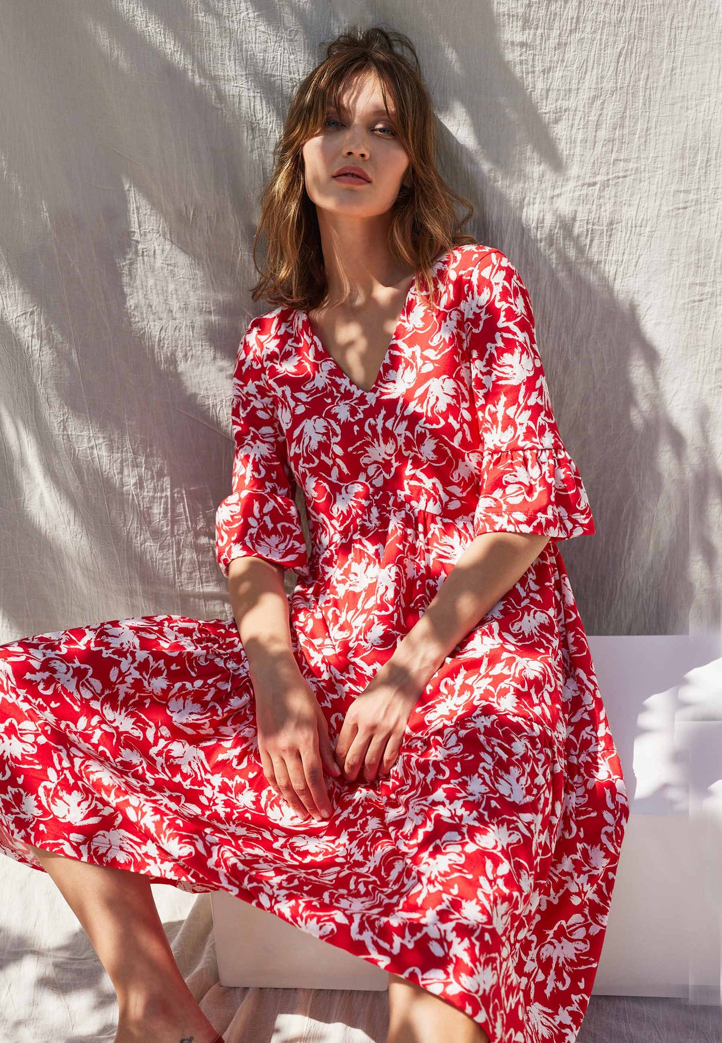 Kleid, Modell Antonia in lebhaftem Rot mit weißem Blumenmuster, V-Ausschnitt und locker fallendem Schnitt, sitzend fotografiert