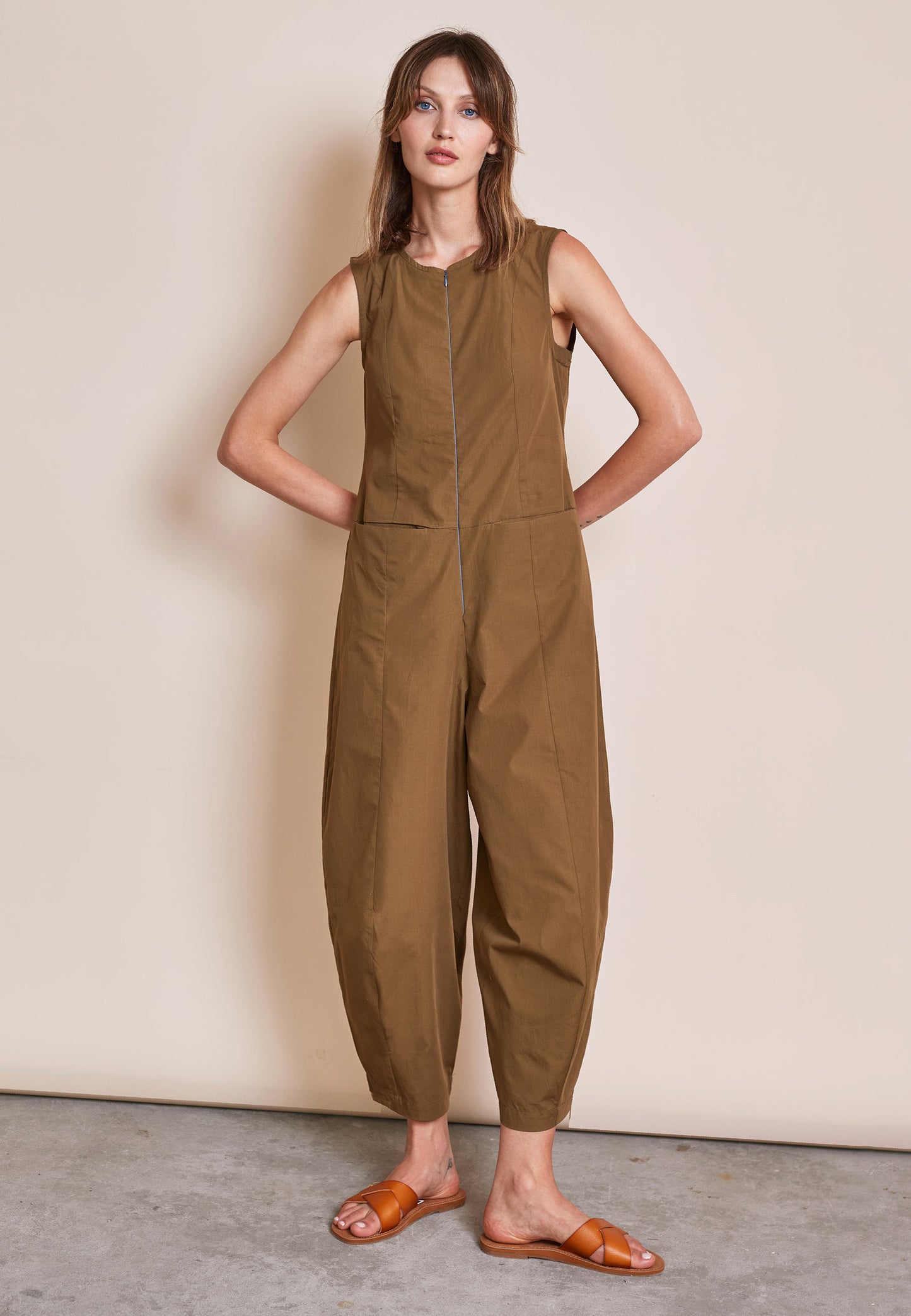 Jumpsuit, Modell Hanja in erdigen Braunton mit Ärmellosigkeit und betonter Nahtführung, frontal stehend getragen