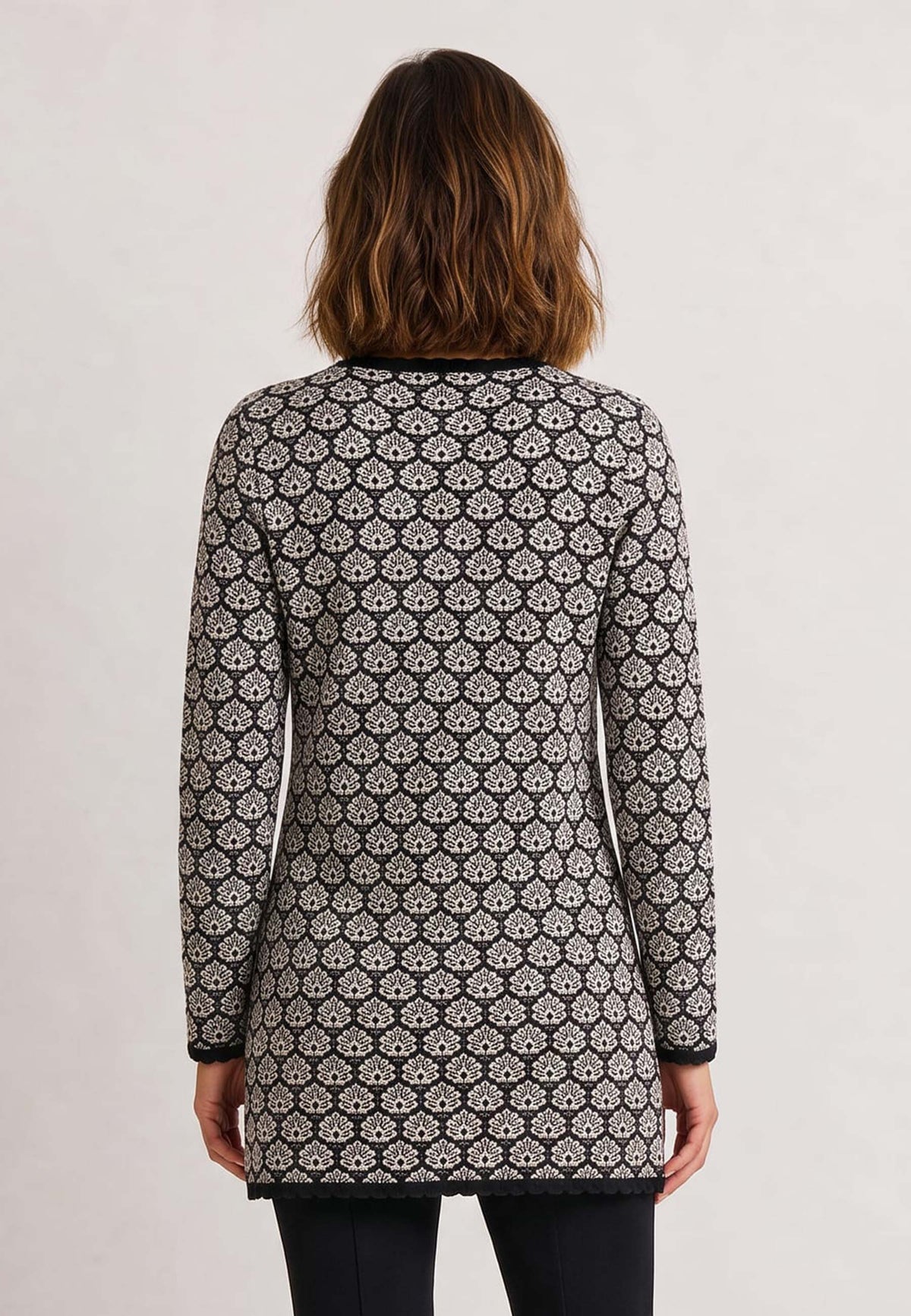 Frau trägt Jacke Eva, Modell lang mit floralem Muster und langen Ärmeln zu schwarzer Hose, Rückansicht