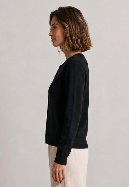 Frau trägt schwarze Jacke, Modell Sophie, zu heller Hose vor neutralem Hintergrund