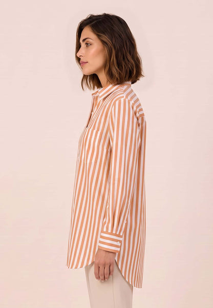 Bluse, Modell Arden mit orange-weißem Streifenmuster an Frau im Profil mit beiger Hose